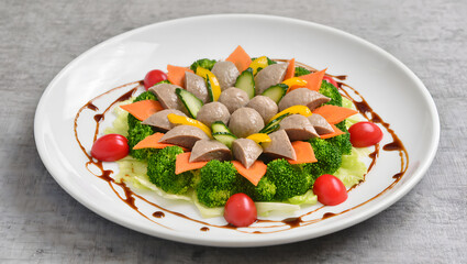 Creative food art presentation of bakso arranged like a flower with vegetables and sauce on a modern plate