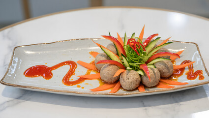 Creative food art presentation of bakso arranged like a flower with vegetables and sauce on a modern plate