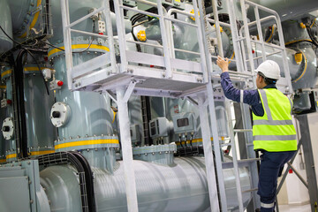 Gas insulated switchgear inspection in substation shows technician climbing ladder for maintenance...