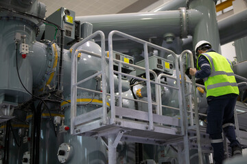Power station staff working on industrial equipment in factory environment with safety gear and...
