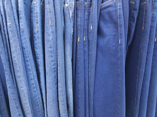 Jeans hanging on hangers in different colors.