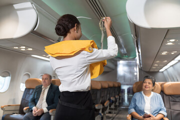 Flight attendant demonstrating safety to passengers inside airplane cabin. Airlines cabin crew...