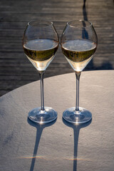 Glasses of white sparkling wine brut, grand reserve, champagne on green hilly vineyards in old wine making grand cru Ay-Champagne village in Vallee de la Marne, Champagne, France