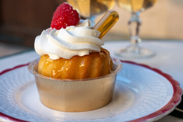French cuisine, fresh baked baba au rum cake with chantilly cream, sweet dessert with rum and glasses of champagne wine close up