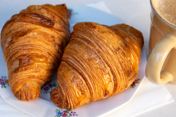 Fresh baked two buttered croissants served with cup of coffee in restaurant for continental or French breakfast on board