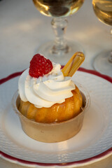 French cuisine, fresh baked baba au rum cake with chantilly cream, sweet dessert with rum and glasses of champagne wine close up