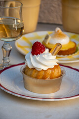 French cuisine, fresh baked baba au rum cake with chantilly cream, sweet dessert with rum and glasses of champagne wine close up