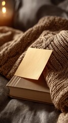 Cozy scene with a book, knitted blanket, and a note on a soft textured background with warm lighting