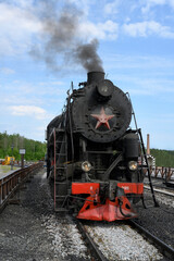 Retro steam locomotive of the mid-20th century with a smoking pipe in Karelia