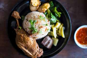 Baked chicken with rice served with many side dish on black dish.