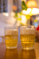 Two glasses of golden beer on table, celebrating friendship and good times.