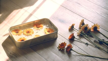 Fresh flowers floating in water in tin tray on wooden surface  