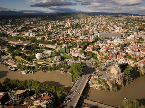 Aerial view of the Mtkvari River snaking through the city, overlooked by the ancient Narikala Fortress and the modern Holy Trinity Cathedral, Tbilisi, Tbilisi, Georgia.