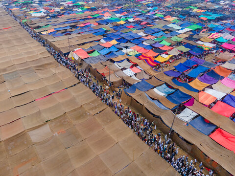 Aerial view of a sprawling tent city, a vibrant tapestry of colorful fabrics stretched over bustling pathways teeming with people, Dhaka, Dhaka Division, Bangladesh.