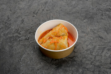 Ukrainian dish stewed cabbage rolls in disposable dishes on a gray background
