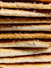 Stacked Saltine Crackers CloseUp of Crispy Texture and Sparkling Salt Crystals.