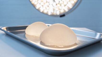 Silicone breast implants on metal tray under surgical light