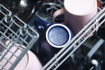 Dirty cups in dishwasher closeup. Top view of open dishwasher with used coffee mugs and kitchen...