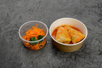 lunch of Ukrainian dishes, cabbage rolls and Korean carrots in disposable dishes