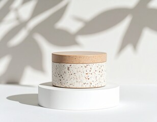 Beige Speckled Cylinder on White Pedestal with Leaf Shadows