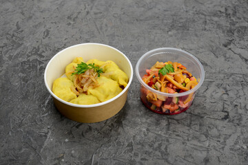 set of mashed potatoes with onions and herbs and salad vinaigrette with mushrooms in disposable dishes on a gray background
