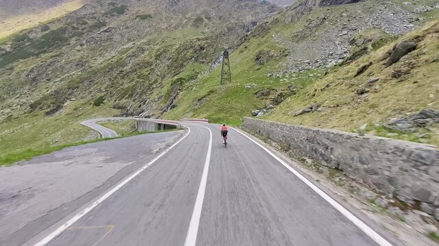 Epic cycling scene on Transfagarasan Highway in Romania. Cyclist rides through breathtaking mountain landscape with sharp turns and stunning views. Perfect for travel, sports, and adventure projects.