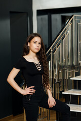 The girl on the stairs indoors she is dressed in black pants and a black blouse