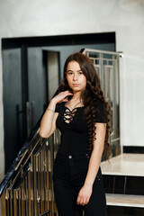 The girl on the stairs indoors she is dressed in black pants and a black blouse