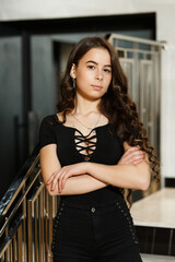 The girl on the stairs indoors she is dressed in black pants and a black blouse