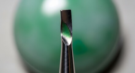Close-up view of a precision instrument, possibly a dental tool, its metallic tip reflecting a blurred green background. The detail is striking, showcasing the tools craftsmanship.