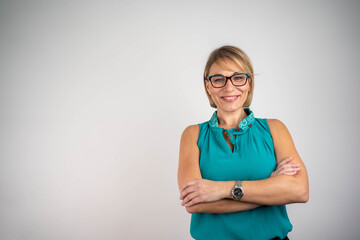 Happy female entrepreneur with arms crossed, confident young businesswoman posing on isolated background in studio