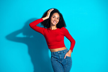 Stylish young woman in red top posing confidently against a vibrant blue background