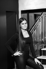 Girl on stairs indoors in leather pants