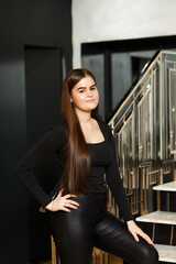 Girl on stairs indoors in leather pants