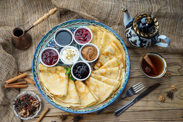 pancakes with fillings in saucers on a wooden background with tea
