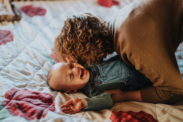 A caring mother enjoys playful bonding with her cheerful baby, creating a heartfelt and joyful...