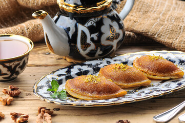 fried sweet oriental cakes on a plate on a wooden background with tea