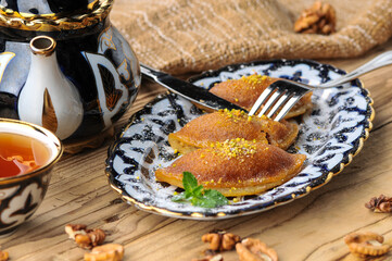 fried sweet oriental cakes on a plate on a wooden background cut with a knife macro photo