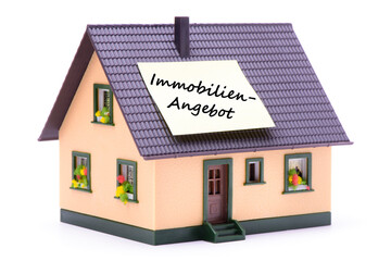 Auf einem Modellhaus klebt ein Zettel mit der Aufschrift Immobilienangebot als Symbol für Immobilienangebot und Hauskauf
