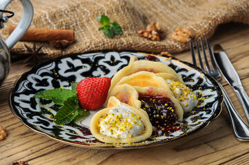 pancakes with jam, cream and preserves rolled into rolls on a beautiful plate on the background