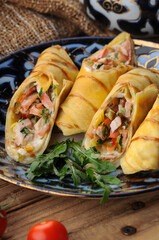 pancakes with filling wrapped in rolls on a beautiful plate in the background macro photo