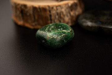 A polished green stone rests on rustic twine-bound sticks against a black background. Minimalist, nature-inspired composition ideal for wellness, meditation, crystal healing, and eco-themed designs.
