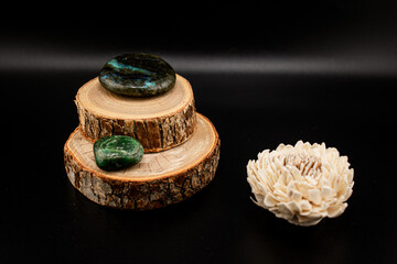 Polished jade and labradorite stones rest on stacked wooden slices  on a dark background. Ideal for...