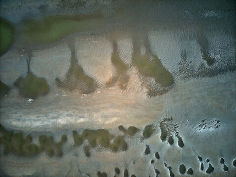Aerial view of the wetlands and waterways create an intricate tapestry of earthy browns, muted greens, and shimmering silvers, Dunkirk, Nord, France.