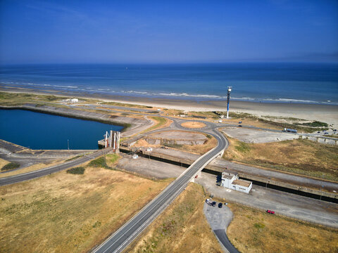 Aerial view of the stark contrast between the deep blue sea and the golden sands, with a striking tower piercing the skyline, Dunkirk, Nord, France.