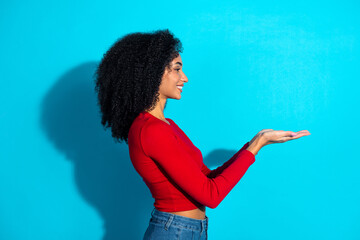 Young stylish woman in a red top gesturing with hands on blue background