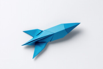 Explore creativity with a minimalist blue origami rocket on a clean white backdrop inviting imagination and wonder