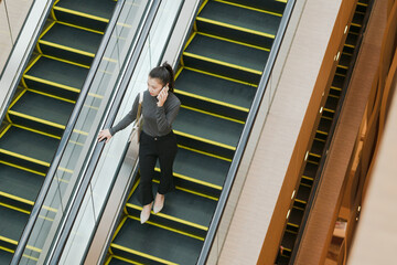 Woman on escalator in shopping mall