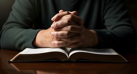Hands clasped in prayer over open bible seeking guidance and faith in spiritual reflection time