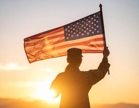 Silhouette of a soldier holding the American flag high against a bright, golden sunset.